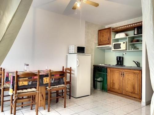 a kitchen with a white refrigerator and wooden cabinets at Studio Balaruc-les-Bains, 1 pièce, 4 personnes - FR-1-503-41 in Balaruc-les-Bains