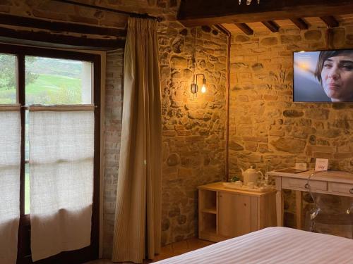 a bedroom with a bed and a tv on the wall at Ca' Virginia Country House Wellness in Montecalvo in Foglia