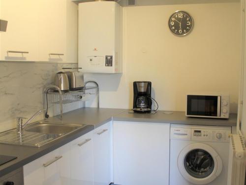 une cuisine avec une machine à laver et une horloge au mur dans l'établissement Appartement *** à Balaruc-les-Bains: Proche Thermes, Équipé, Balcon, Parking - FR-1-503-111, à Balaruc-les-Bains