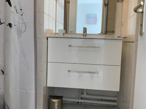 une salle de bain blanche avec un lavabo et un miroir dans l'établissement Appartement climatisé à Balaruc-les-Bains avec balcon, parking et animaux admis - FR-1-503-127, à Balaruc-les-Bains