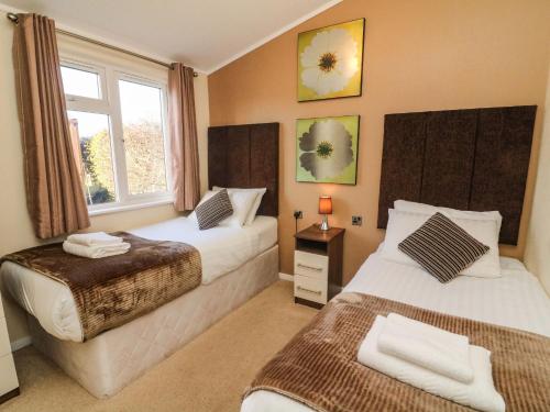 Un dormitorio con dos camas y una ventana. en Dream Catcher Lodge, en Carnforth
