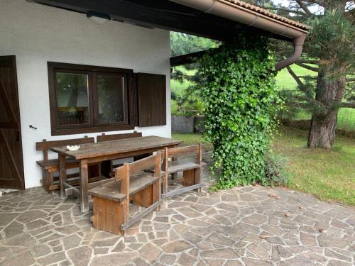 uma mesa de piquenique de madeira e banco ao lado de um edifício em La casa di carlo em Lavarone