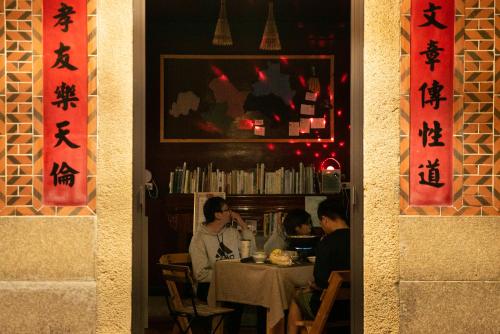 um grupo de pessoas sentadas numa mesa num restaurante em 斜坡客棧 KIVALA Hostel em Jincheng