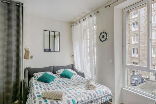 Un dormitorio con una cama con almohadas verdes y una ventana en Saint-Malo intramuros - Port à 30M et plage à 200M, en Saint-Malo