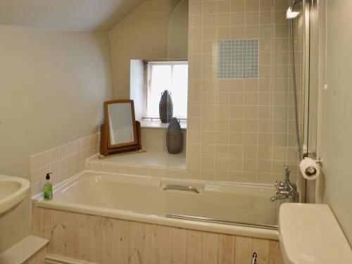 a bathroom with a tub and a sink and a mirror at Georges Cottage - Hsss in Clovelly