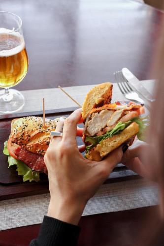 a person holding a sandwich on a plate with a glass of beer at Cottage Carrasco in Montevideo