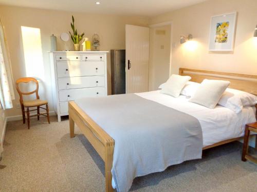 a bedroom with a white bed and a dresser at The Old Winery Cottage in Dymock