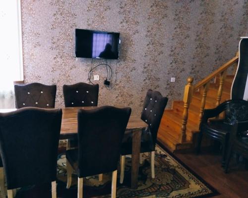 ein Esszimmer mit einem Tisch und einem TV an der Wand in der Unterkunft Gabala red villa in Qəbələ