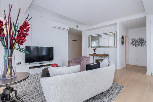 a living room with white furniture and a tv at Le Se7t Penthouses in Montréal