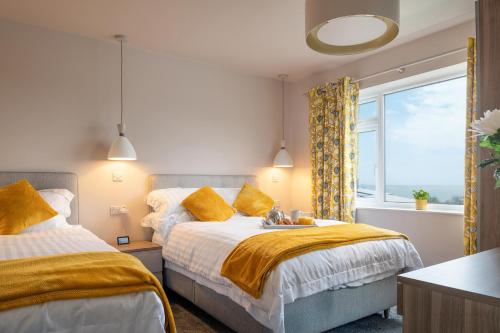 a bedroom with two beds and a window at Cartref in Benllech