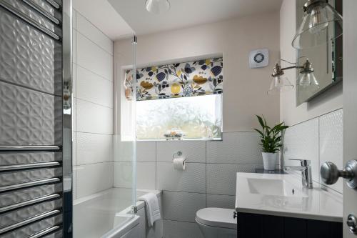 baño con lavabo y aseo y ventana en Cartref en Benllech