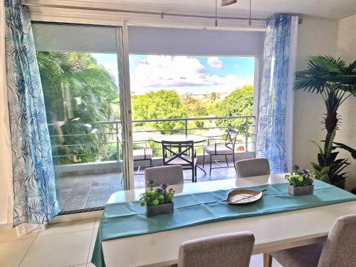 a dining room with a table and a balcony at OASIS Penthouse with private garden & shared pool in Koolbaai