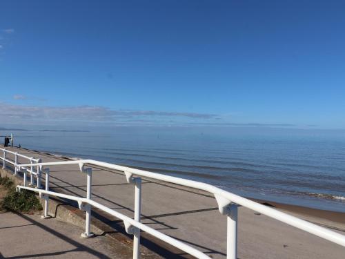 a white railing on a beach with the ocean at The Nest in Prestatyn