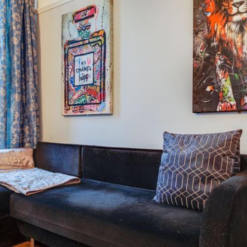 a black couch in a living room with paintings at Somerset House in Bangor