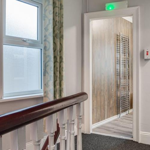 a hallway with a staircase with a window and a mirror at Somerset House in Bangor