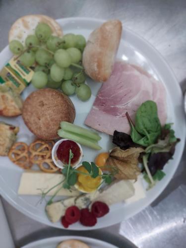 a white plate of food with grapes and meat at Grains Bar Hotel in Oldham