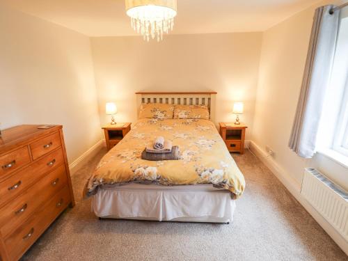 a bedroom with a bed with a dresser and two lamps at Thames Cottage in Hull