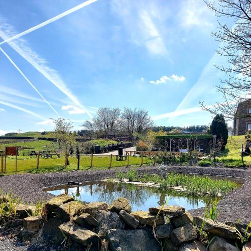 a pond in a park with a rock wall at Grains Bar Hotel in Oldham
