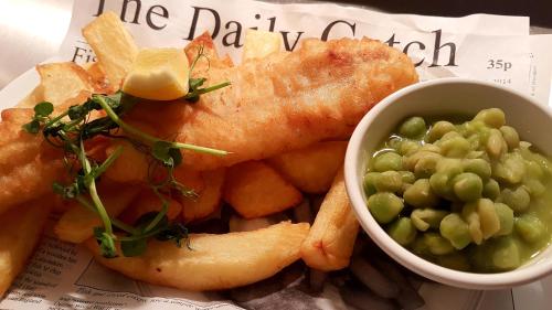 a plate of food with fish and chips and peas at Grains Bar Hotel in Oldham