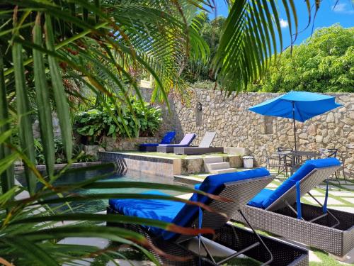 a pool with chairs and umbrellas next to a pool at OASIS Penthouse with private garden & shared pool in Koolbaai