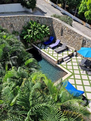 a swimming pool with chairs and umbrellas and palm trees at OASIS Penthouse with private garden & shared pool in Koolbaai