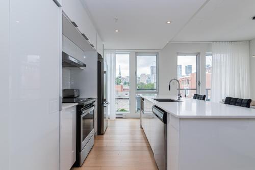 a kitchen with white counters and a large window at Le Se7t Penthouses in Montréal