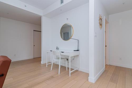 a white dining room with a white table and a mirror at Le Se7t Penthouses in Montréal