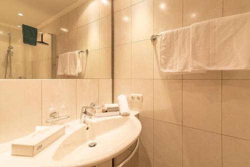 a white bathroom with a sink and a mirror at Hotel Garni Martina in Ischgl
