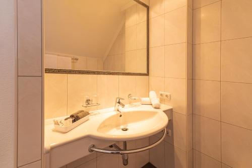 Baño blanco con lavabo y espejo en Hotel Garni Martina, en Ischgl