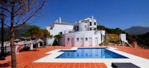 a swimming pool in front of a white building at Stylish 3 bed house 2 bathrooms with patio, roof terrace and communal pool 5 minutes away from the beautiful Spanish white village of Casares Pueblo and only 20 mins from the sea in Casares