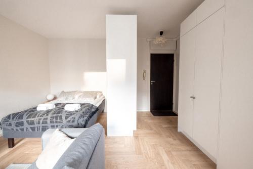 a white bedroom with a bed and a couch at 2ndhomes Cozy high-quality Studio in Kluuvi with Balcony in Helsinki