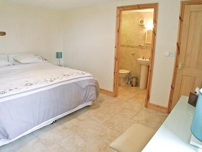 a bedroom with a bed and a bathroom at Orchard Cottage in Westward