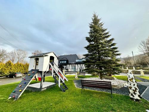 a playground with a slide and a tree and a house at Apartamenty Pruskie in Karpacz