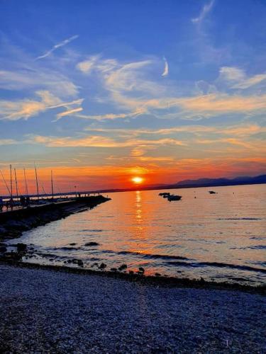 a sunset over the ocean with boats in the water at Una Rosa sul Mincio in Valeggio sul Mincio