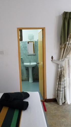 シギリヤにあるSigiri Holiday Villaのベッド、洗面台、鏡が備わる客室です。