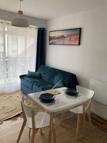 a living room with a blue couch and a table at La Baie L’Etoile, Apt 4 pers, bord de mer, parking privé, Fort Mahon Plage in Fort-Mahon-Plage