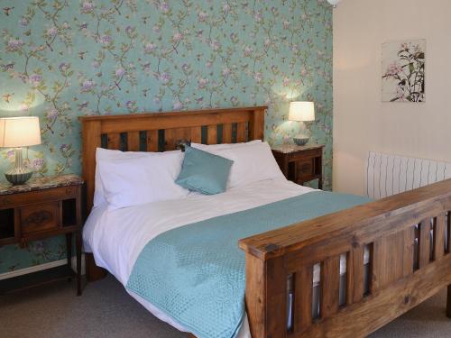 ein Schlafzimmer mit einem Holzbett mit blauen und grünen Tapeten in der Unterkunft Rosies Retreat in Whitby