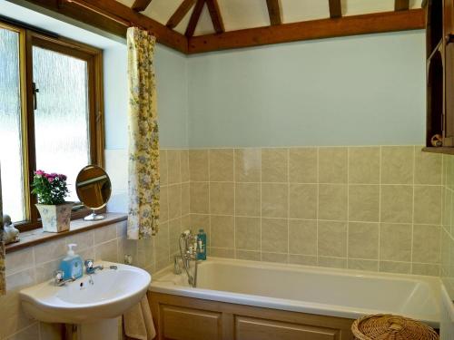 a bathroom with a sink and a bath tub at Ivy Cottage in Sandhurst