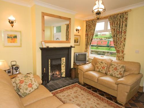 a living room with two couches and a fireplace at Hollybush Cottage - E2800 in Cheddleton