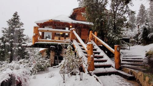 a log cabin in the snow with snow covered stairs at Cabaña Del Árbol in San Martín de los Andes