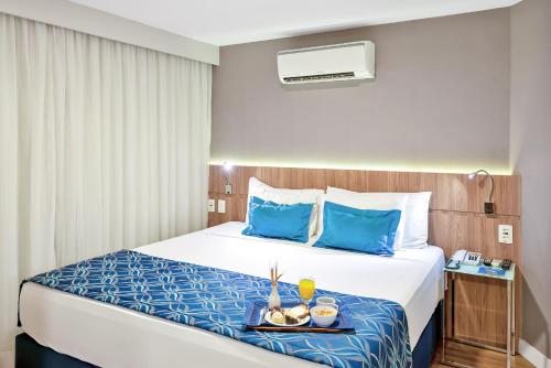 a hotel room with a bed with a tray of food on it at Blue Tree Garden Bauru in Bauru