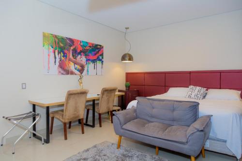 een slaapkamer met een bed, een tafel en een bank bij Hotel Itatiaia in Tangara da Serra