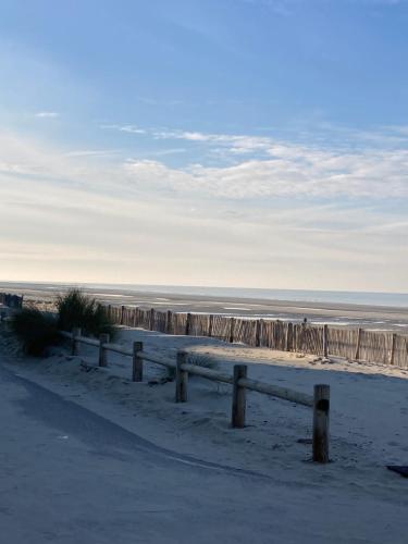 a sandy beach with a fence and the ocean at La Baie L’Etoile, Apt 4 pers, bord de mer, parking privé, Fort Mahon Plage in Fort-Mahon-Plage