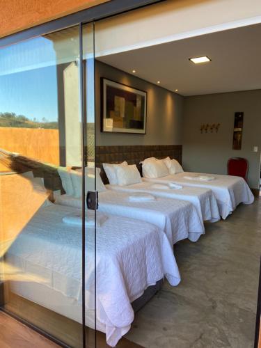 Duas camas num quarto com uma parede de vidro em Pousada Guardiã da Canastra em Vargem Bonita