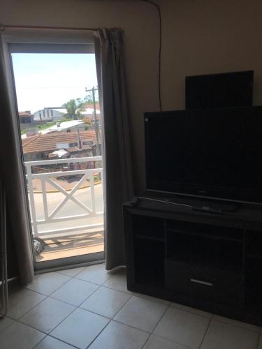 sala de estar con TV y puerta a un balcón en Playa 497 en Pinamar