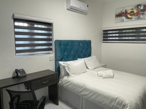 Liso’s Place Guest House في بريتوريا: غرفة نوم مع سرير مع اللوح الأمامي الأزرق ومكتب