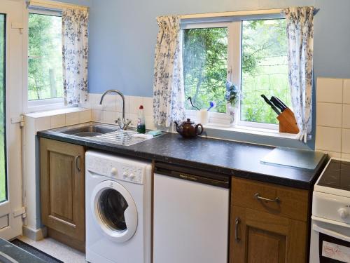 uma cozinha com uma máquina de lavar roupa e um lavatório em Ryecroft em Bradwell