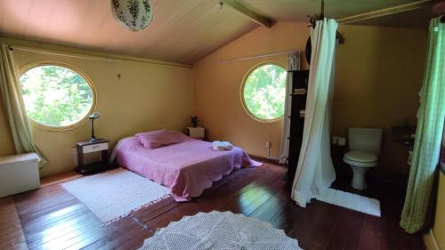 a bedroom with a pink bed and two windows at Chalés Manhana- Água in Alto Paraíso de Goiás