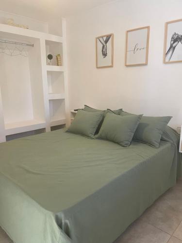 1 cama con sábanas y almohadas verdes en una habitación en Departamento céntrico Colón en Colón
