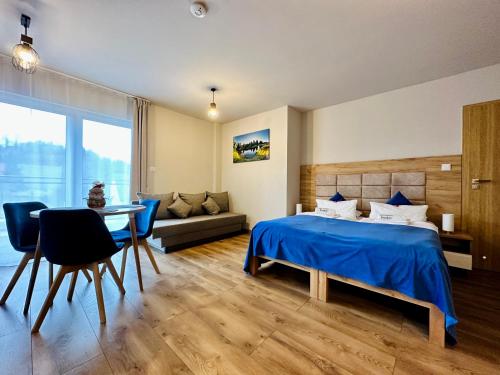 een slaapkamer met een bed, een tafel en een bank bij Apartamenty Pruskie in Karpacz